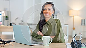 Proud, happy and confident business woman typing on a laptop and turns to look at the camera in her office. Portrait of