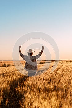 Proud happy victorious wheat farmer with hands raised in V