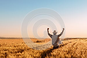 Proud happy victorious wheat farmer with hands raised in V