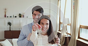 Proud happy young couple holding keys standing in new apartment