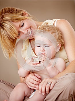 Proud of her little boy. Cute baby boy being held by his smiling mother while holding something.