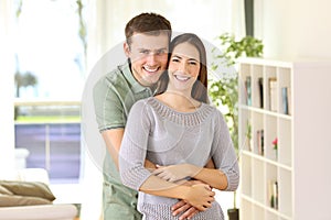 Proud homeowners posing looking at you at home photo