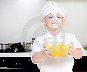 Proud little boy chef with a face full of flour