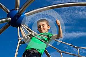 Proud little boy climbs the play structure at the playground