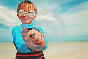 Proud little boy found seashells on beach