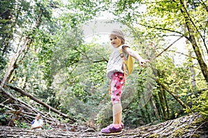 Proud little girl scout standing on a log in the woods