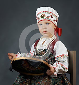 Proud little girl in the traditional russian sarafan during embroidering