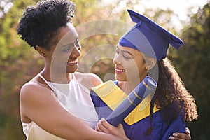 Proud Mother Celebrating With Teenage Daughter Wearing Graduation Robes Outdoors photo
