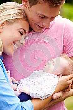 Proud Parents Holding Baby Daughter In Garden