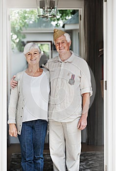 Proud patriots. A happy senior man standing with his wife wearing his old army uniform - portrait.