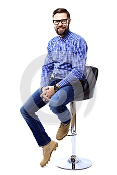 Proud and satisfied young man sitting on chair and looking at camera isolated on white