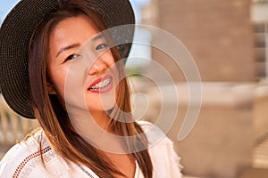 Proud smile of a girl not embarrassed by braces, a girl of Asian appearance in a hat and white T-shirt