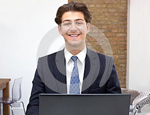 Proud smiling young businessman at his desk