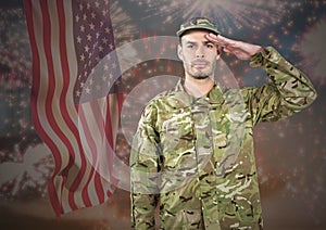 Proud soldier saluting against fluttering american flag and fireworks in background