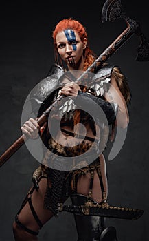 Proud and strong woman viking holding an axe in dark background