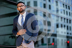 Proud successful businessman executive CEO african american, standing confidently with arms folded in downtown, financial building photo