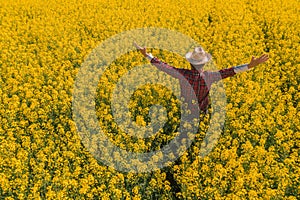 Proud successful oilseed rape farmer in blooming field