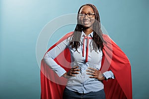 Proud superhero woman with superpower abilities wearing mighty hero cloak while smiling confident at camera.