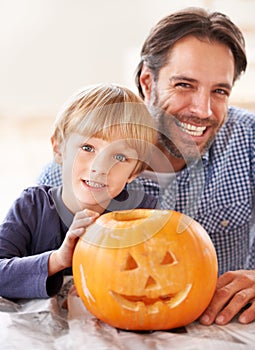 Proud of their jack-o-lantern. Portrait of a father and son behind their carved pumpkin for halloween.