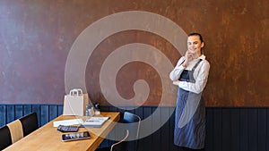 Proud woman entrepreneur in apron looking at camera in restaurant