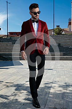 Proud young elegant man walking in red velvet tuxedo