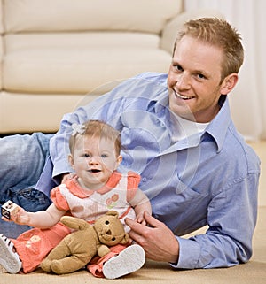 Proud young father playing with baby daughter