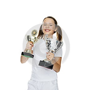 Proud young girl holding two trophies