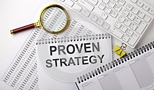 PROVEN STRATEGY text written on notebook on the chart with keyboard and planning