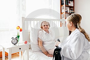 Providing care for elderly. Doctor visiting elderly patient at home.