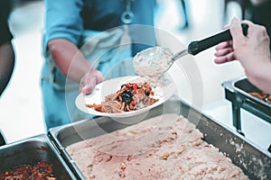 Providing free food to the poor : Volunteers scooping out food to give charity to those who are hungry