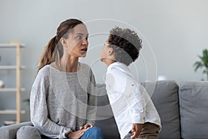 Provocative mixed race little kid demonstrating impolite behavior to mom.