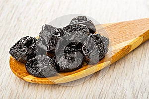 Prune in spoon on wooden table