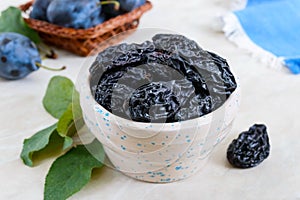 Prunes in a clay bowl and fresh plums, leaves