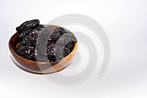 Prunes isolated on white background, dried plums collection in a brown wooden bowl isolated