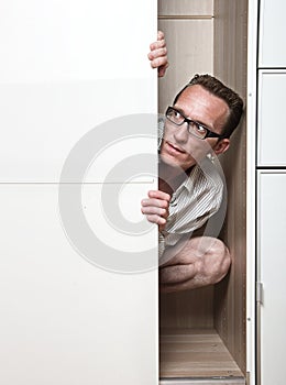 Prying man hiding inside white wardrobe photo