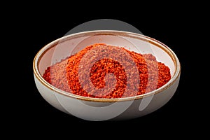 PSD ground paprika in a bowl isolated on black