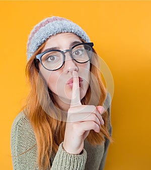 Psst. Young woman holding finger on lips,keep the secret concept, isolated on yellow background photo