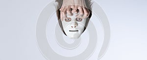 Psychedelic surrealistic concept. Lost thoughts. The head in a white mask without a body is held by crooked fingers. Template for