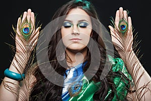 Psychic abilities psychics communicate with spirits. Beauty portrait of girl holding peacock feathers, bright clothes