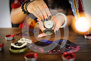 Psychic readings and clairvoyance concept - Crystal ball fortune teller with hands hold retro pocket watch and Tarot cards reading