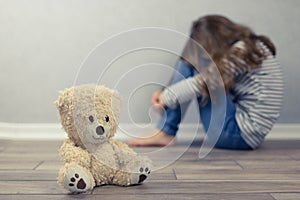 Psychological health concept. A teddy bear and in the background a teenage girl out of focus. Psychological assistance to children