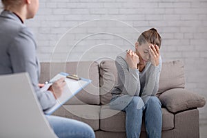 Psychological help concept. Millennial woman with depression having counseling session with therapist at office