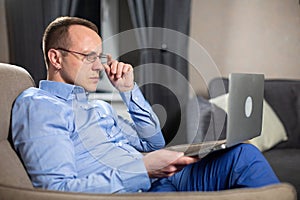 Psychologist with glasses working hard with laptop on lap