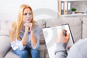 Psychologist talking with depressed female patient in office