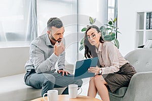 psychologist talking with male patient and showing clipboard