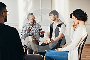 Psychologist talking about twelve-step program to addicted man during group support meeting photo