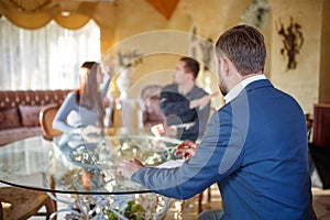 At the psychologist. Young couple sitting at a glass table quarrel, doctor sitting in a chair listening