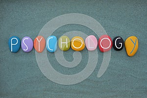 Psychology text composed with multicolored stone letters over green sand