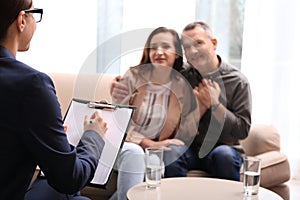Psychotherapist and happy couple having meeting in office