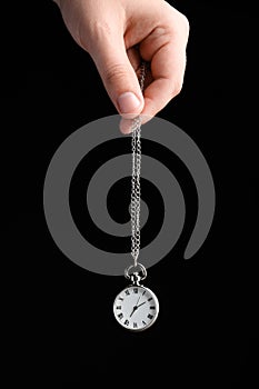 Psychotherapist with pendulum on black background, closeup. Hypnotherapy session